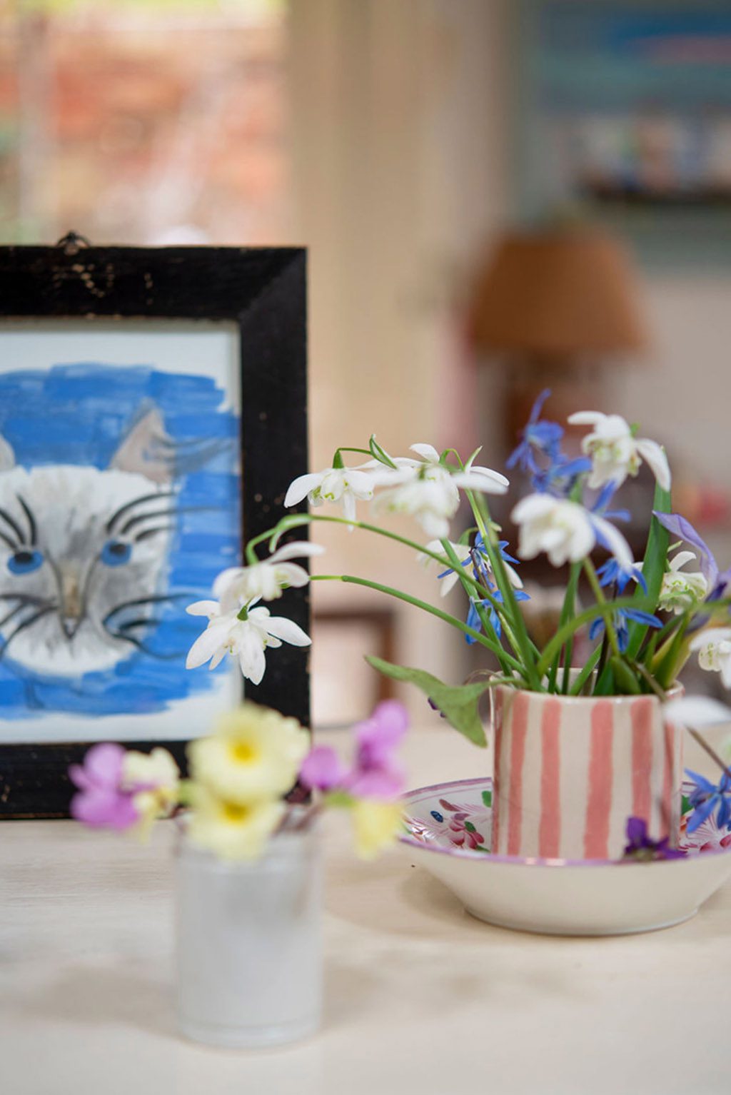 Framed picture of cat and vases of spring flowers.